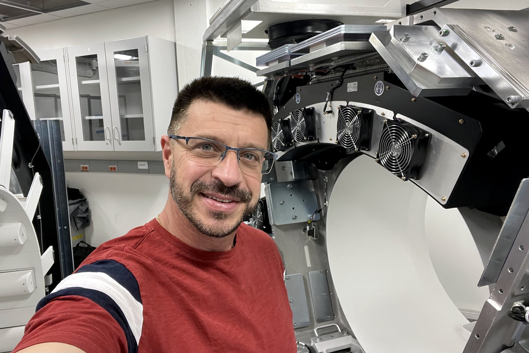 Leonid Strugatsky at an open CT gantry during service, cover removed and cooling fans exposed
